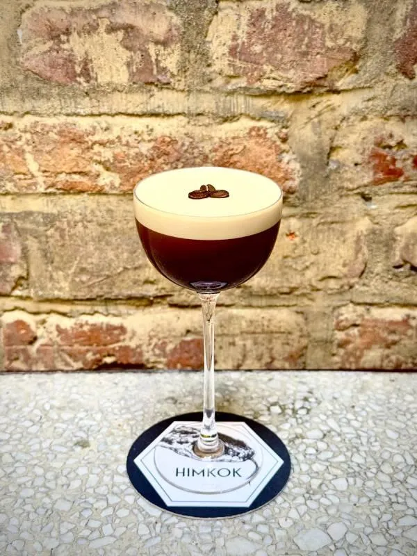 person holding cup of cocktail mix on table