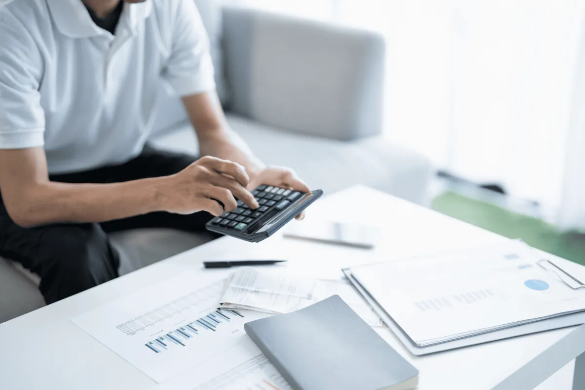 Person using calculator with financial papers on a table