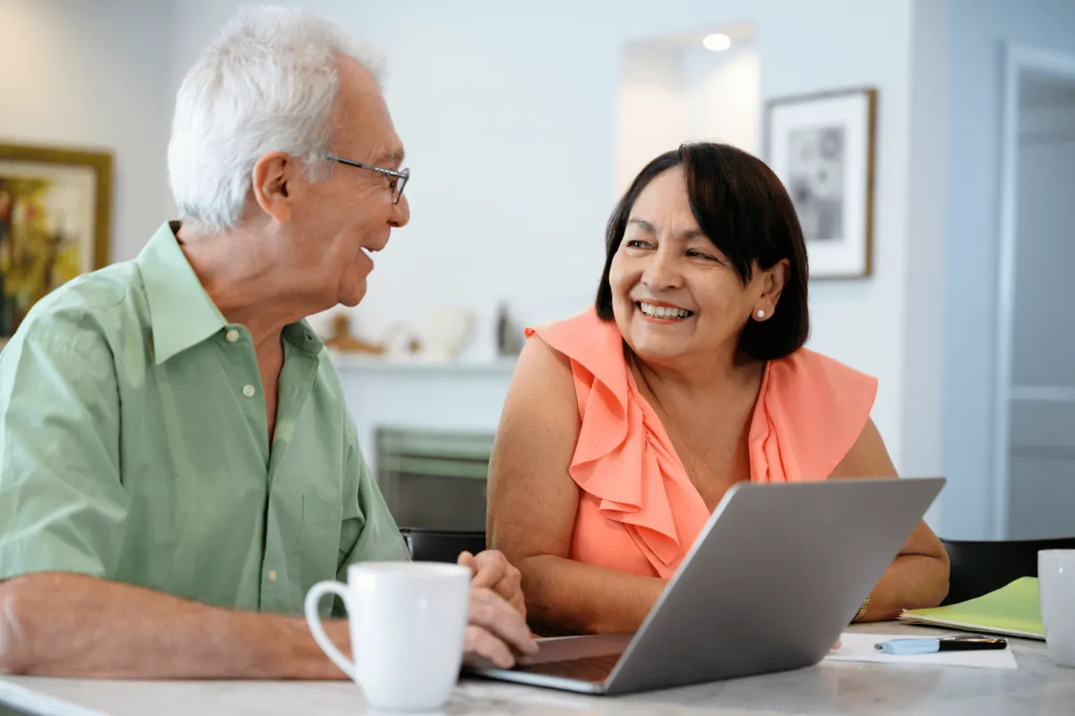 Older couple smiling at laptop while reviewing finances
