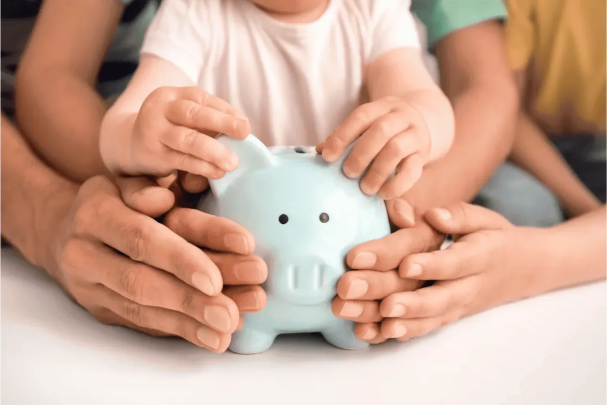 Child and parents holding a light blue piggy bank together