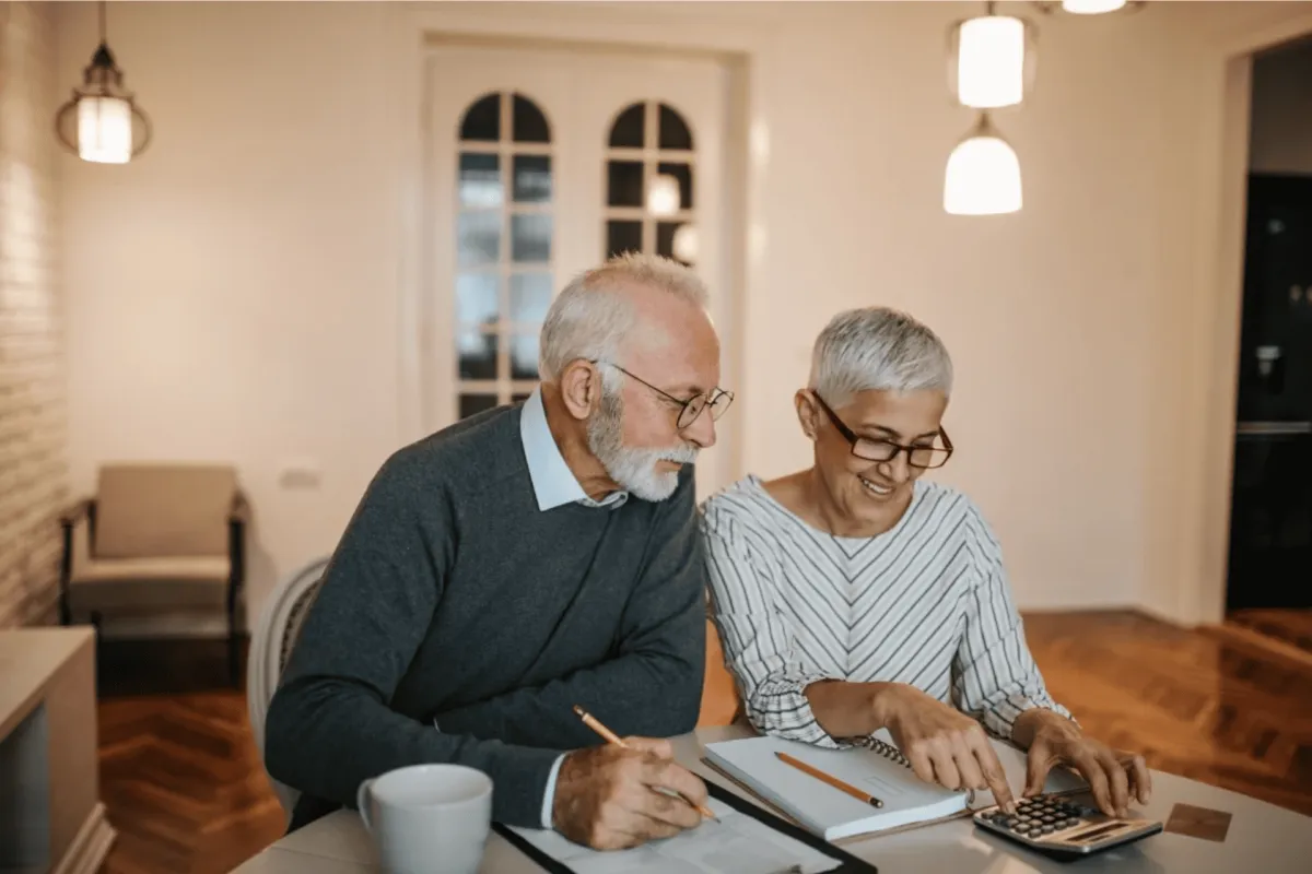 Older couple reviewing finances together at home with a calculator