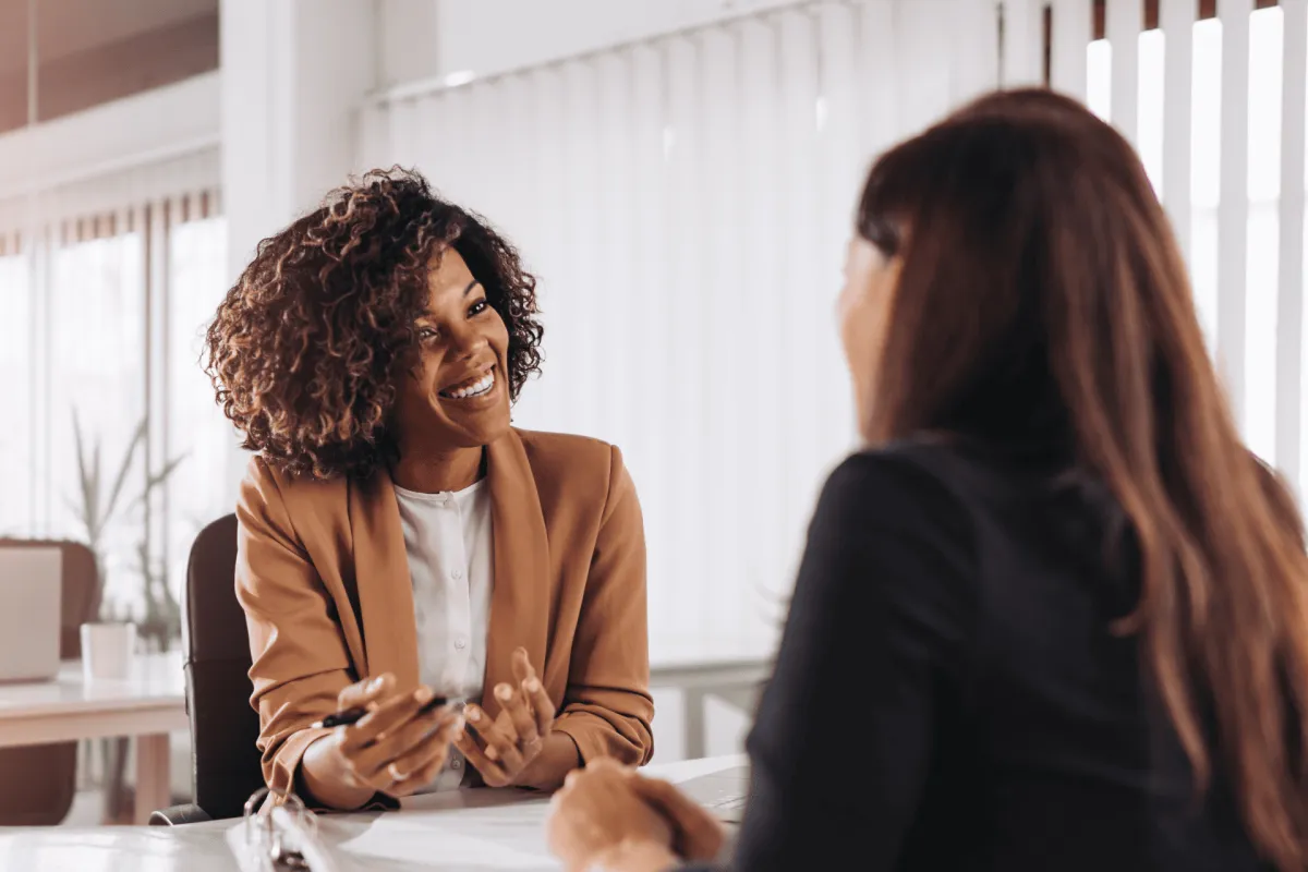 Smiling professional speaking with a client across a desk