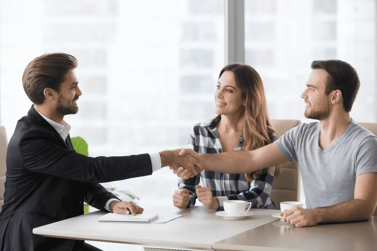 Financial advisor shaking hands with a young couple in an office