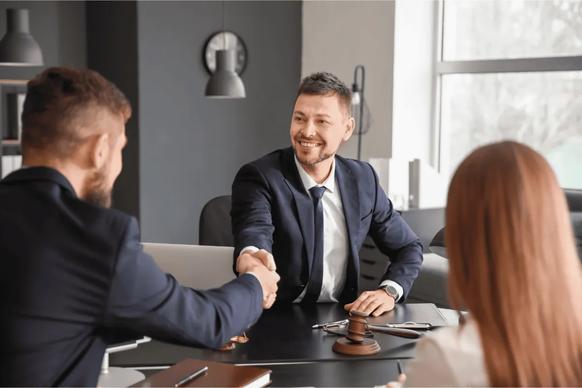 Business professional shaking hands with clients across a desk