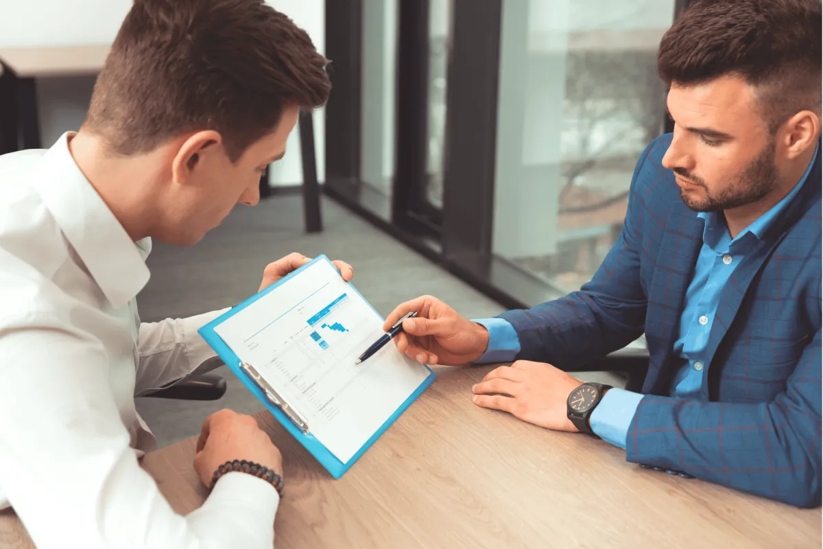 Two men reviewing a financial report together at a desk