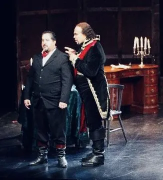 James Nathanel Salazar rehearses with a full orchestra in a grand hall. The conductor is visible in the foreground, musicians are attentive, and the space features high ceilings and polished wooden floors, highlighting the collaborative energy of preparation.