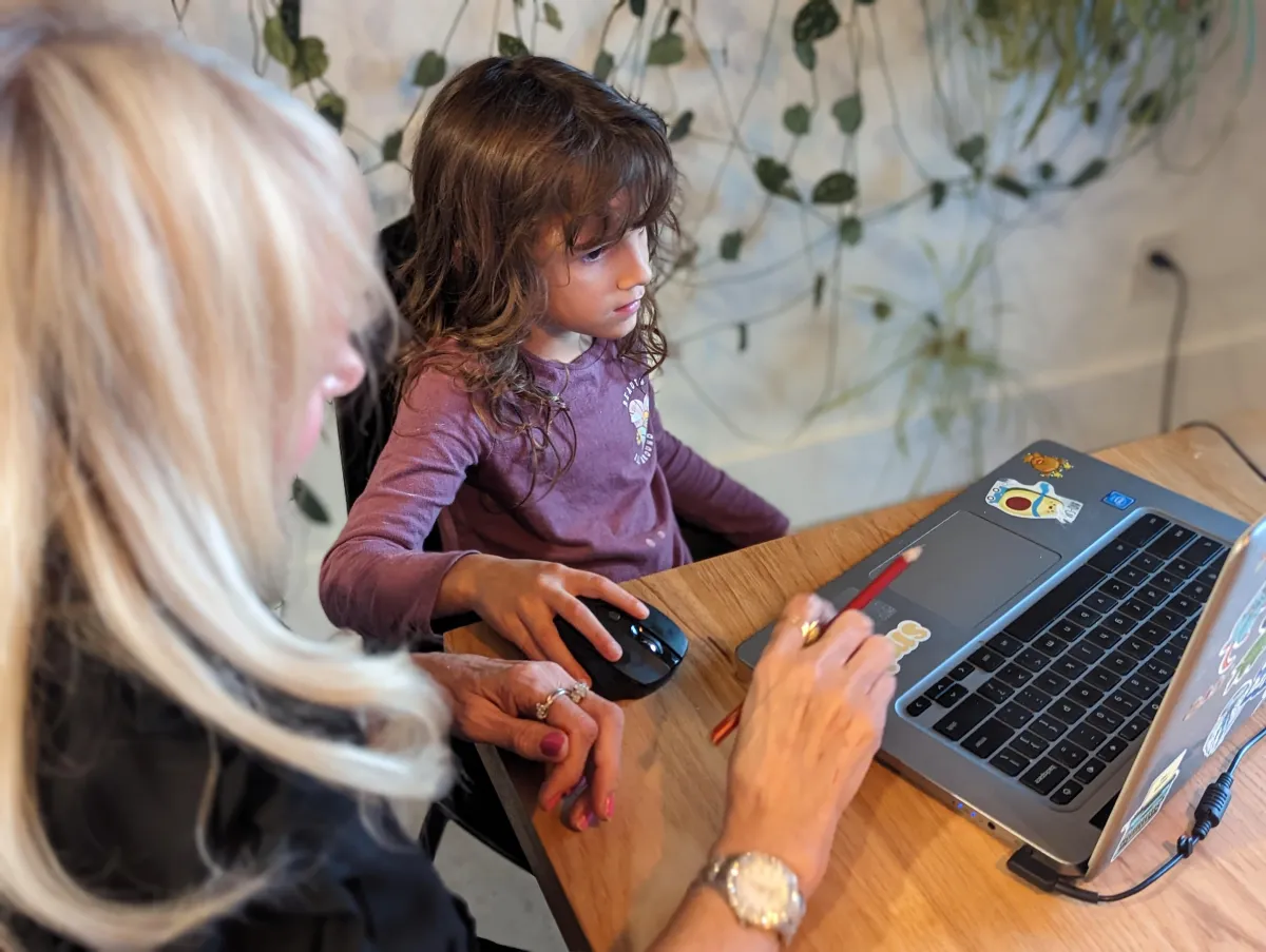 Private tutor instructing a kindergarten student on a computer