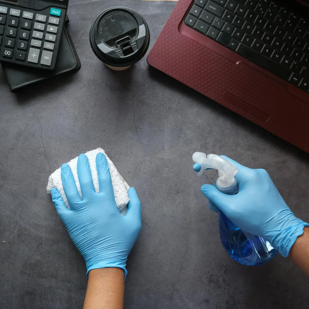 As smiling Cosmic Cleaning employee wearing light blue gloves and squeegee cleaning a window.