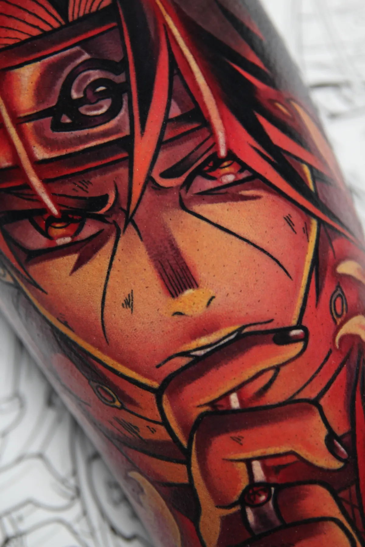 Large anime tattoo of Itachi from Naruto by Orlando Anime Tattoo Artist Ren Behan. This Itachi tattoo features him doing the fire release attack using a vibrant monochromatic palette of reds and oranges.