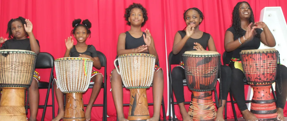 African Soul International youth musicians smiling and playing percussion instruments in community circle