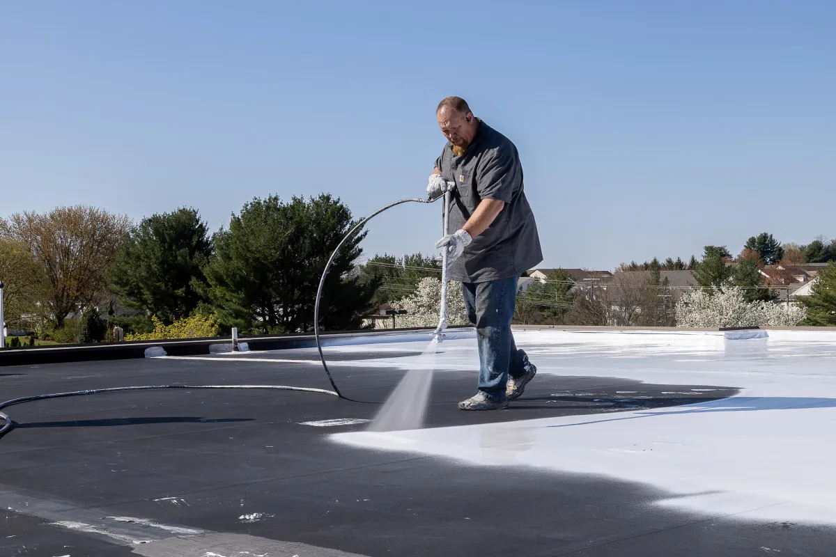 Tim Schultz of Schultz Roofing applying silicone roof coating to a commercial roof in Central PA.