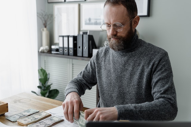 a person sitting at a desk counting money