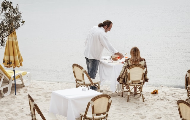 a person serving a person at a table on a beach