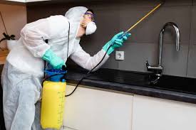 a person in a white suit spraying chemicals