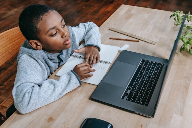 a child sitting at a table with a laptop