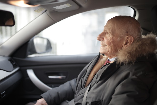 an old  person smiling in a car