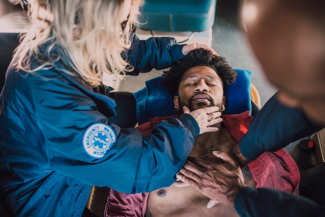 a person lying on a chair with a person touching his head