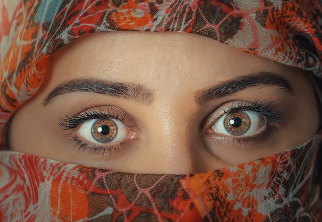 a person with brown eyes and a scarf over her face