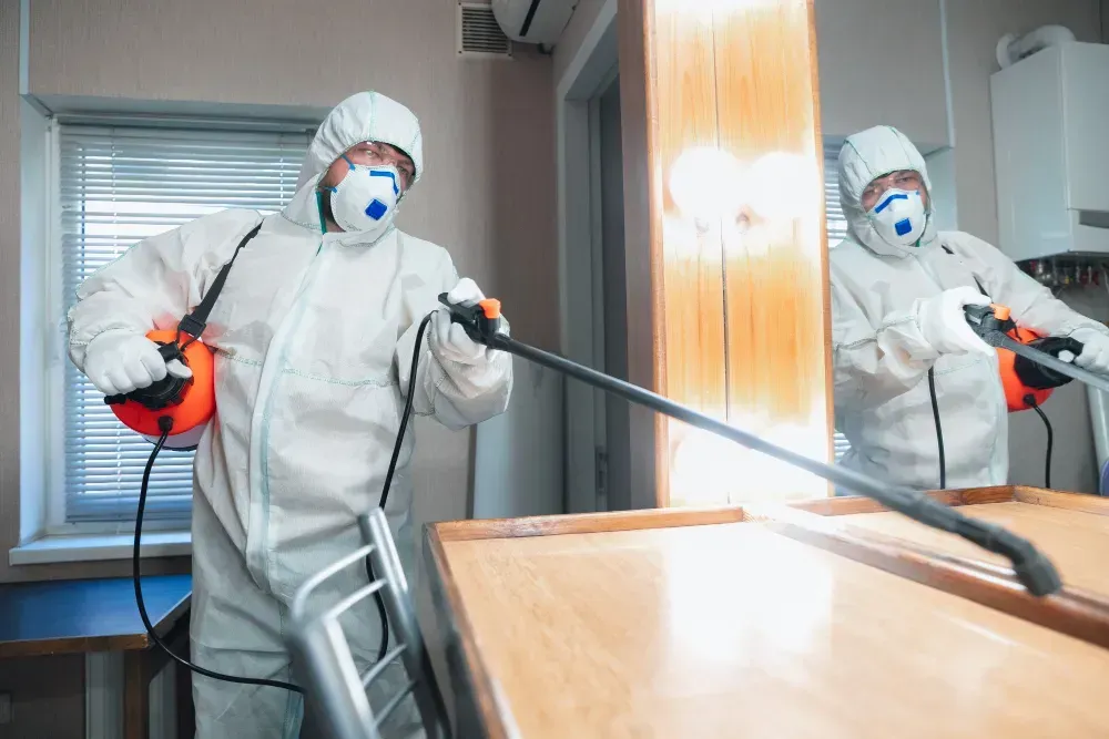 a person in hazmat suit spraying a table