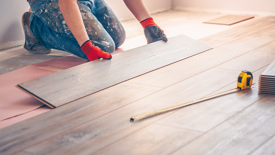 a person wearing gloves and holding a wood floor