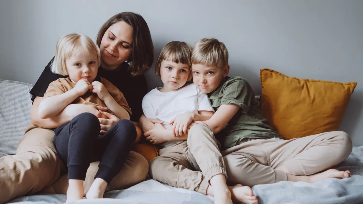 Mum of 3 sitting on the couch with kids cuddling