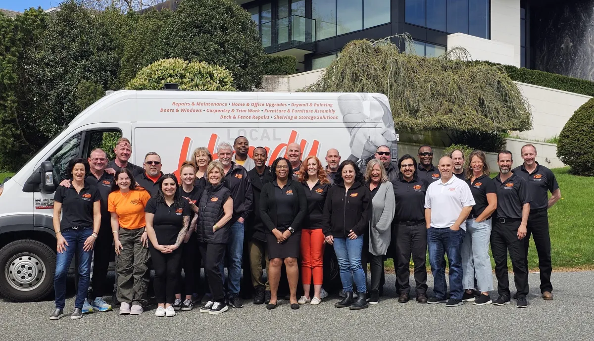 Local Handyman Group franchise team standing together in front of a branded service van, representing handyman franchise opportunities and support network.