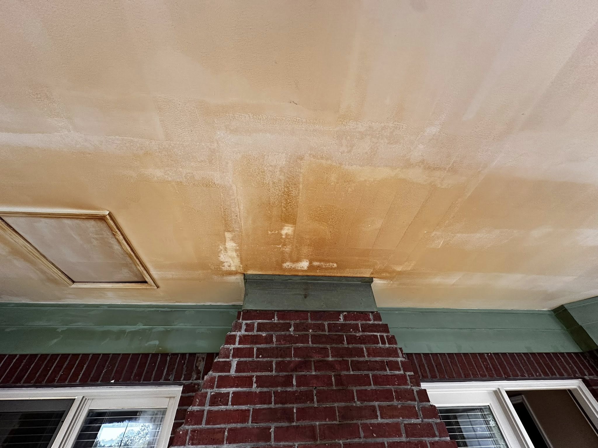 Image of a porch ceiling with heavy moisture staining and discoloration above brick trim, illustrating how Memphis humidity and poor loess-soil drainage trap moisture in exterior soffits. Shows the real early-stage wood rot conditions Local Handyman Midsouth repairs across older Bluff City homes.