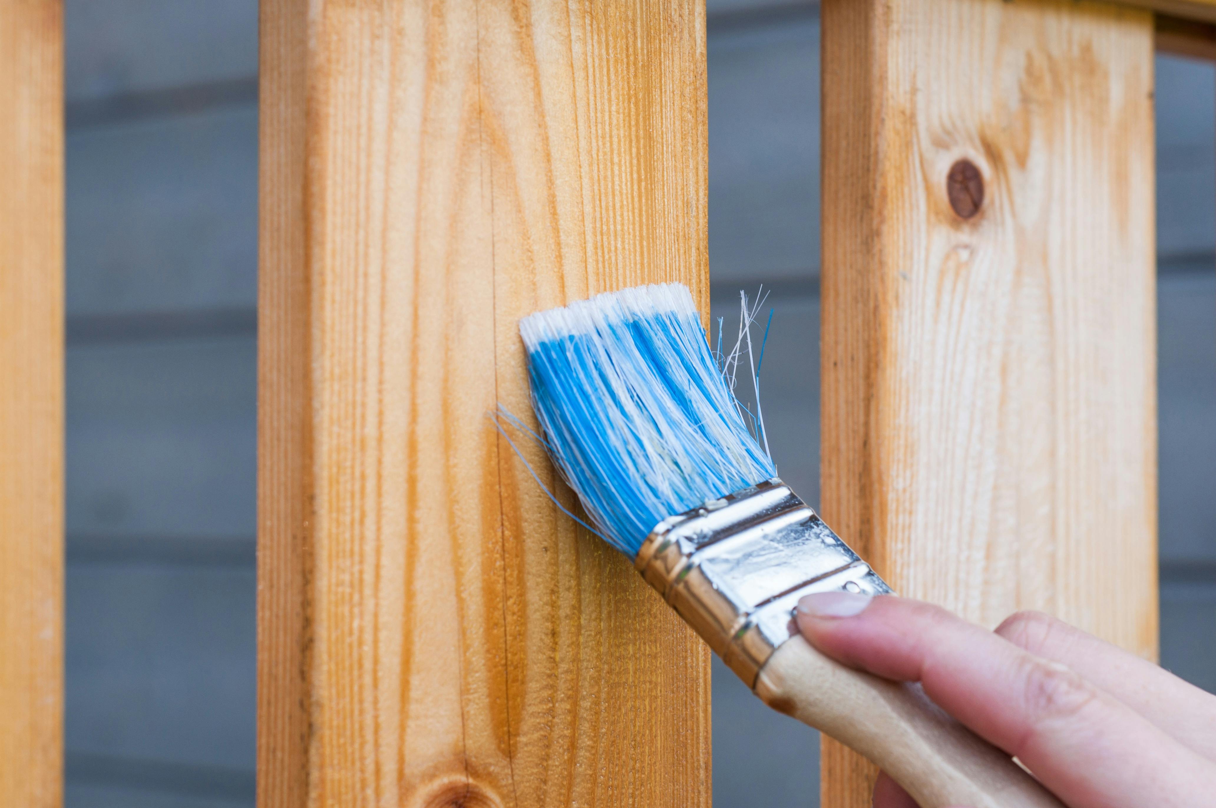 Image showing a fence picket being brushed with protective coating, demonstrating how Memphis humidity and rapid wet–dry cycles require sealing to prevent warping, rot, and fastener loosening. Illustrates preventive maintenance Local Handyman Midsouth provides during fence repair.