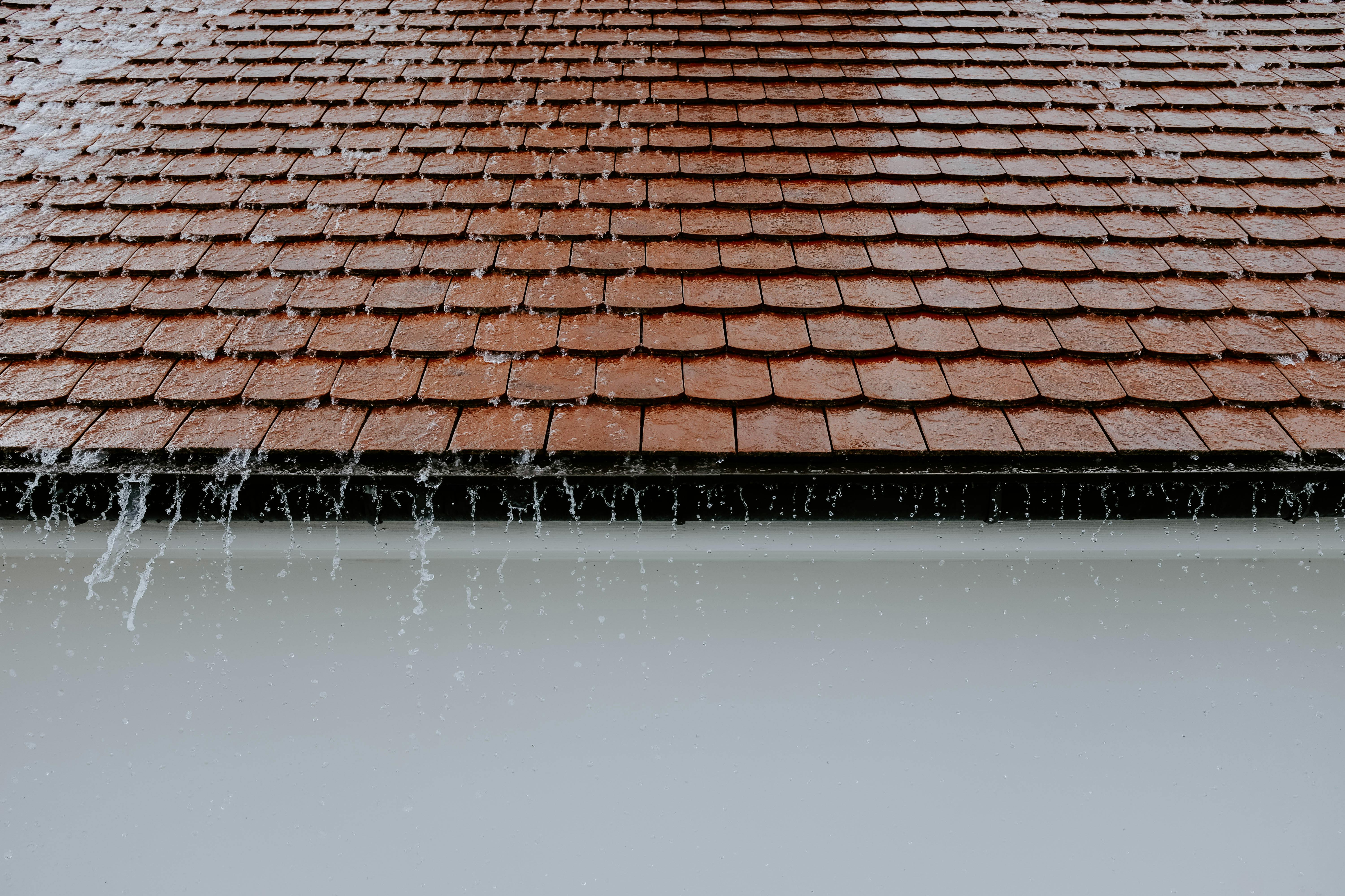 Image of rainwater spilling over a roof edge, illustrating how Memphis storms and silty loess-soil runoff quickly clog gutters and push water toward the foundation. Captures the real symptoms Local Handyman Midsouth resolves during seasonal cleanouts.
