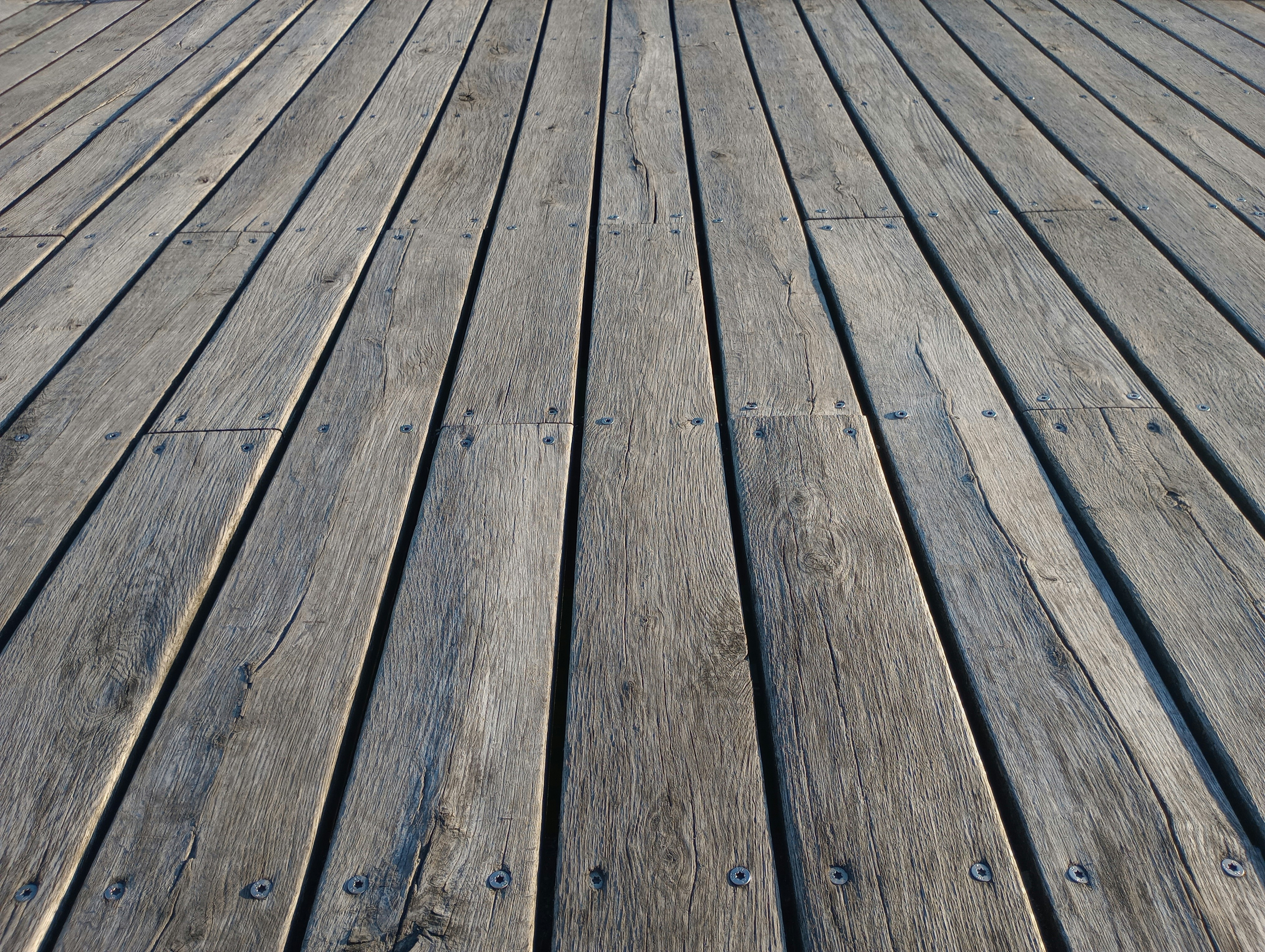 Wide shot of a heavily weathered deck surface, showing warped and grayed boards caused by Memphis UV intensity and abrasive storm grit. Reflects the real conditions Local Handyman Midsouth restores before applying high-solids stain.