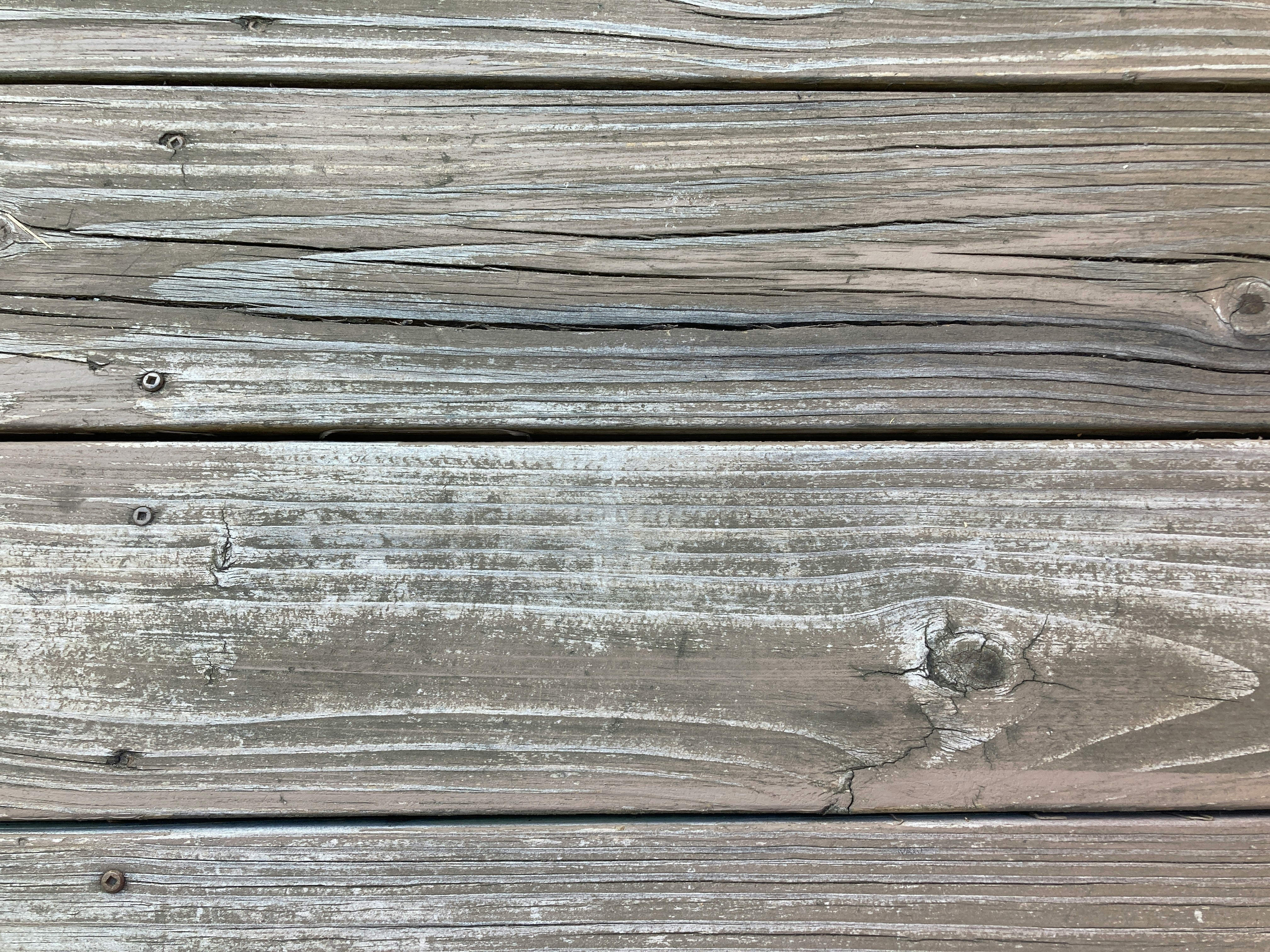 Close-up of aging deck boards with UV fading and moisture-wicking patterns typical in Memphis yards where loess soil keeps vapor rising under decks. Shows the surface wear Local Handyman Midsouth treats before staining or full prep.