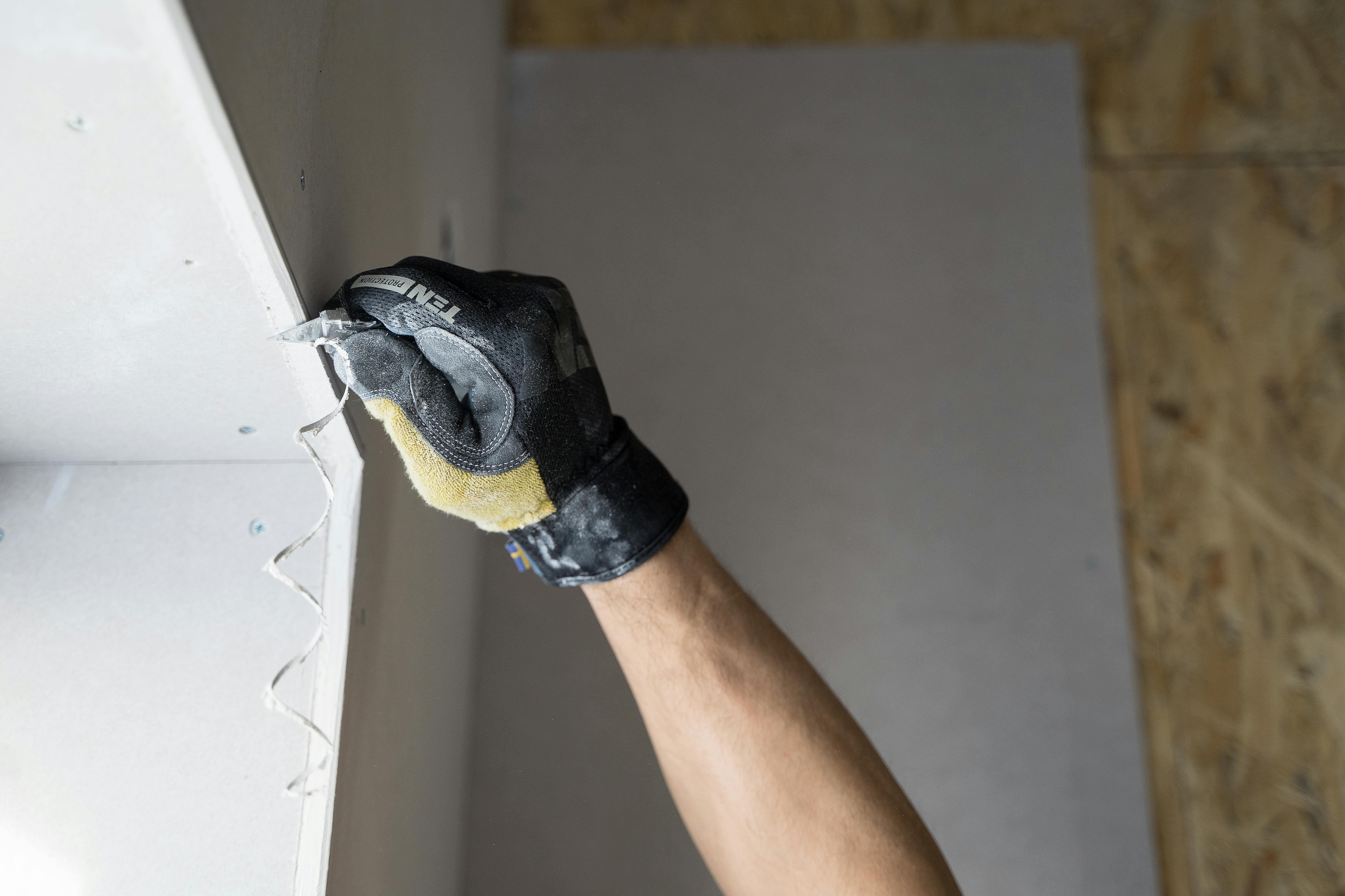 Close-up of a technician cutting back loose plaster, showing the prep work needed in Memphis homes where loess soil sway and rapid storm-pressure drops open cracks along old walls. Demonstrates Local Handyman Midsouth’s detailed stabilization process.