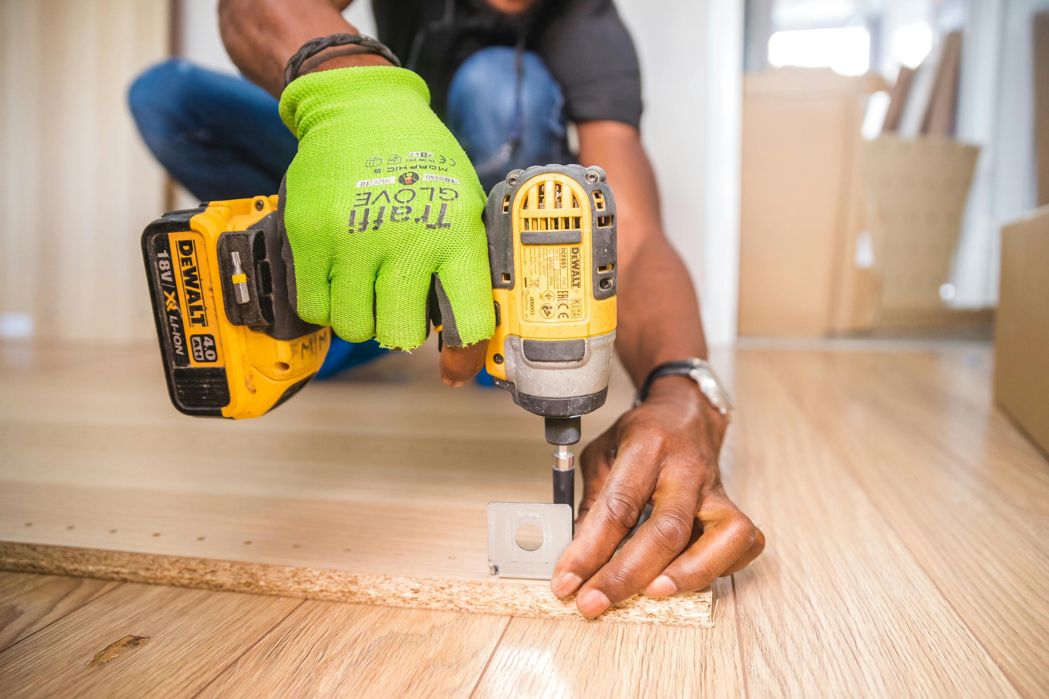 Skilled handyman using a power drill to install hardware into engineered wood flooring, representing professional, licensed workmanship in a Memphis home.