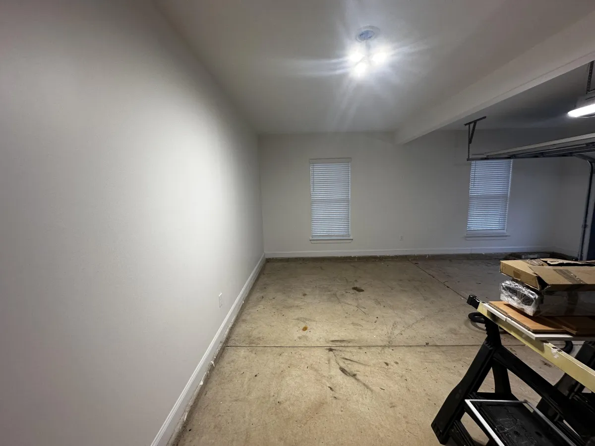 Empty garage in a Memphis home with exposed concrete slab and finished walls, showing structural conditions that often relate to squeaky floors above.