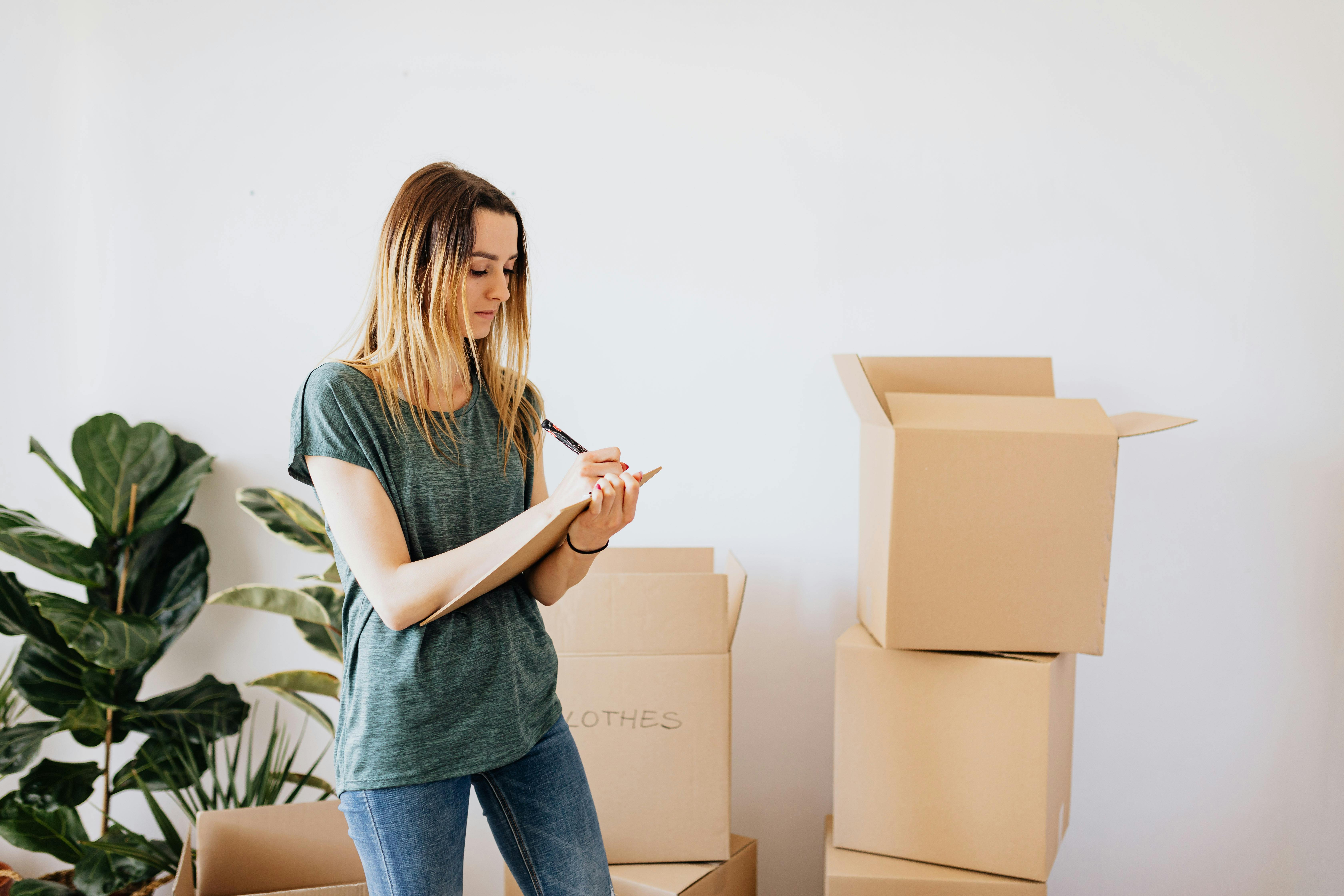 Homeowner writing a checklist next to moving boxes, representing planning and prioritizing home maintenance tasks in Memphis.