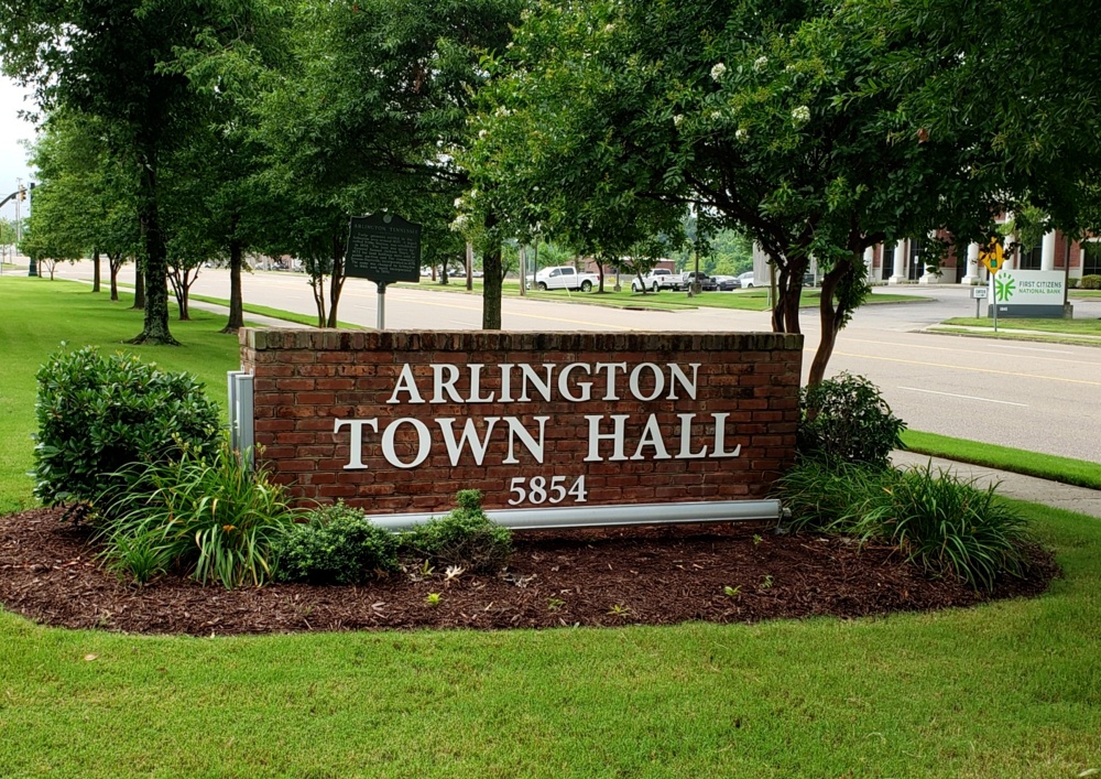 Arlington Town Hall sign in Arlington, Tennessee surrounded by mature trees and well-maintained landscaping along a main road.
