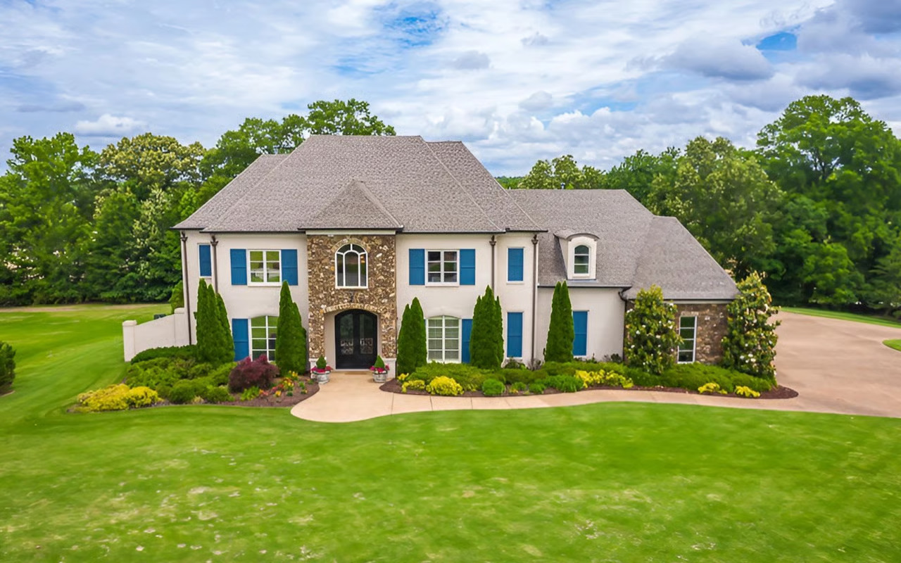 Large custom home in Eads, Tennessee with stone exterior, manicured lawn, and mature trees typical of upscale Mid-South residential properties.