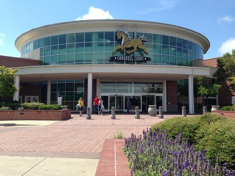 Entrance to a large retail shopping center near Eads, Tennessee with glass facade, pedestrians, and landscaped walkways.
