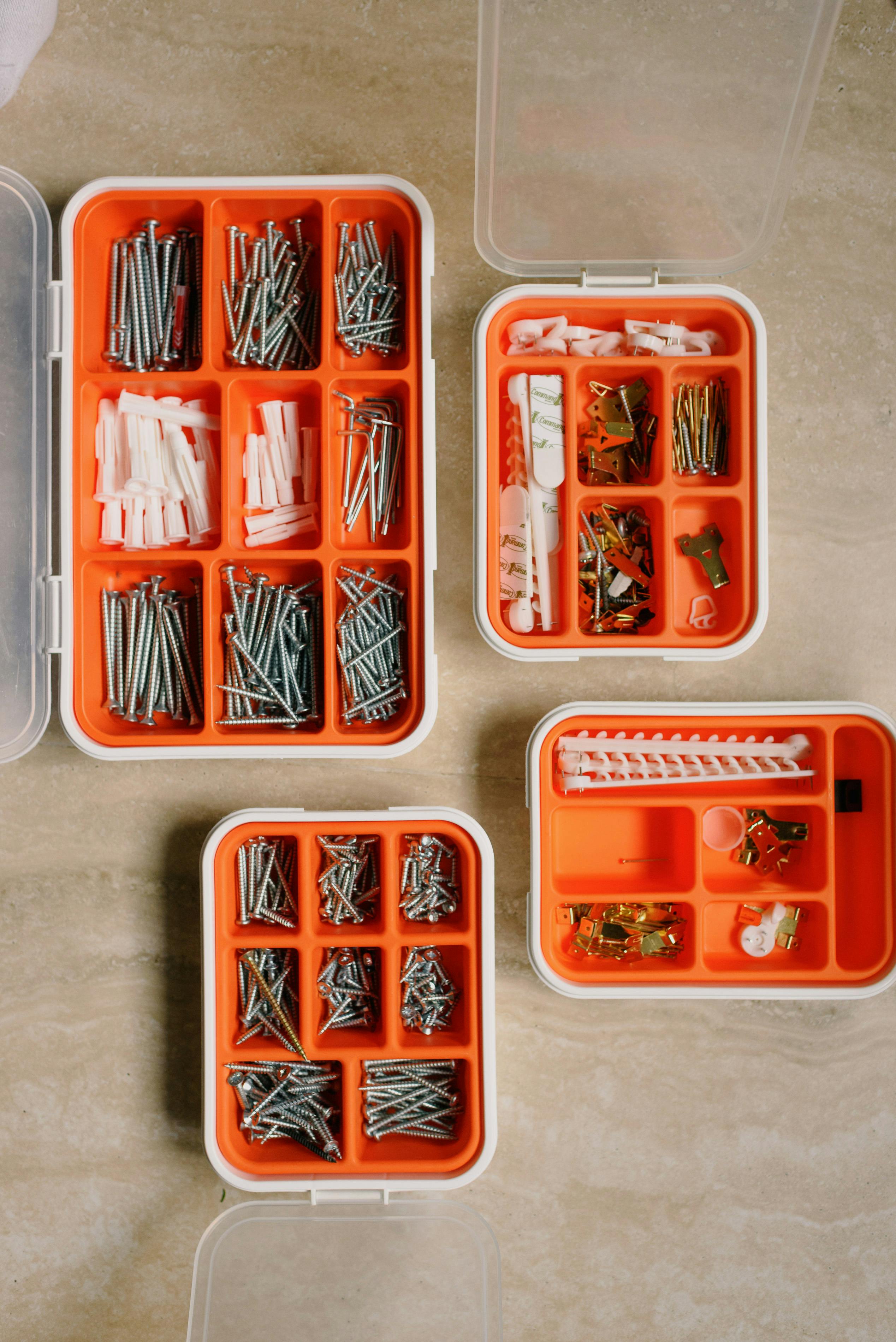 Organized storage boxes filled with screws, anchors, brackets, and mounting hardware for home repair projects.