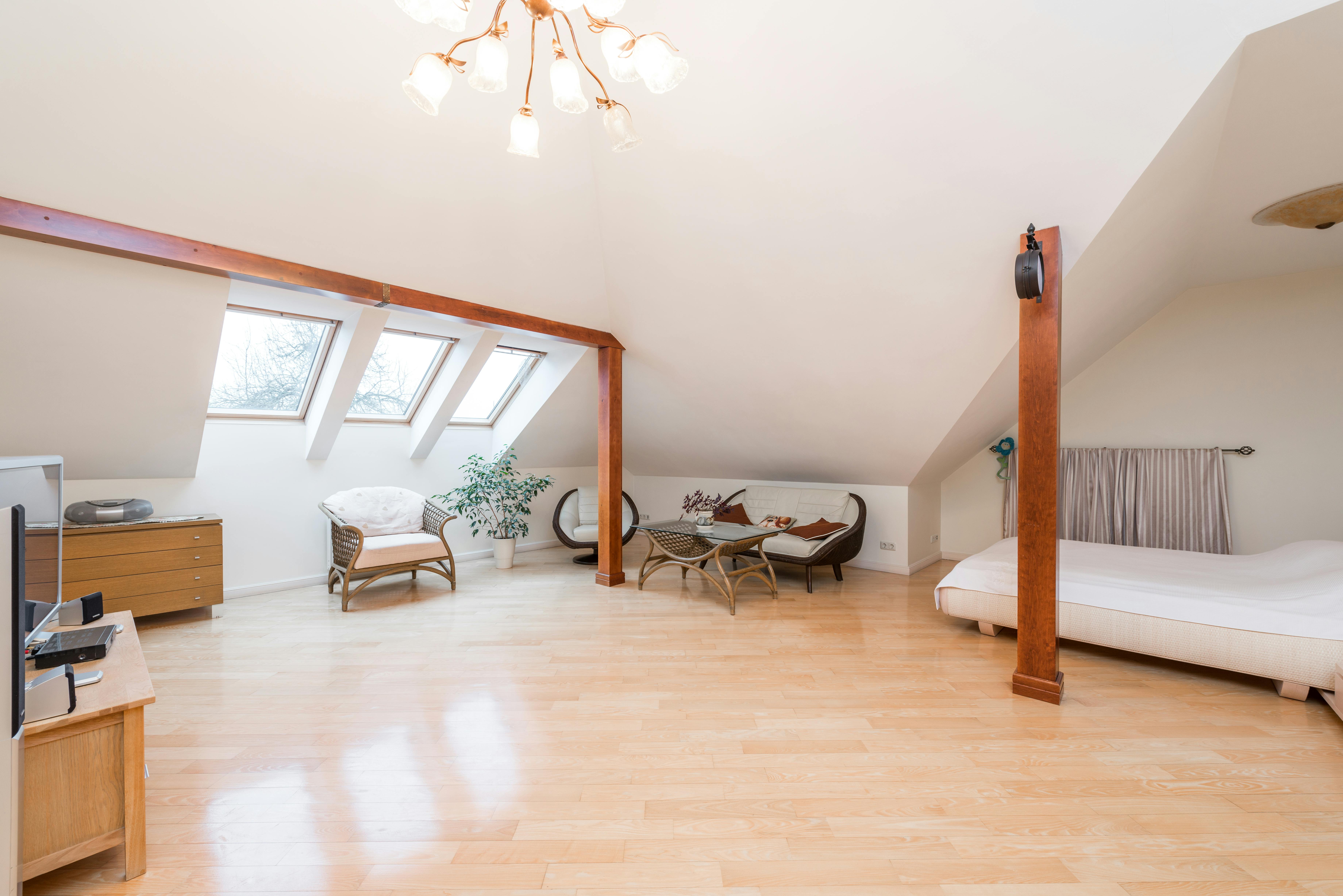 Open finished attic loft with hardwood floors, skylights, exposed beams, seating area, and bedroom space.