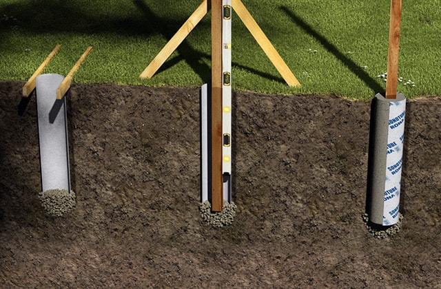 Fence posts positioned in concrete form tubes and gravel base with level tool used for proper alignment.