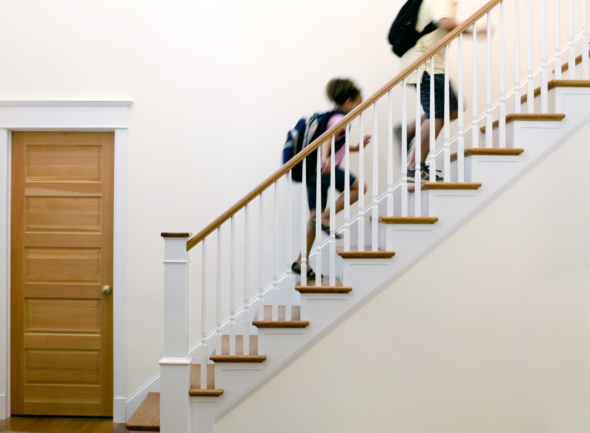 Family walking up a well-maintained interior staircase with repaired railings and finished wooden steps.