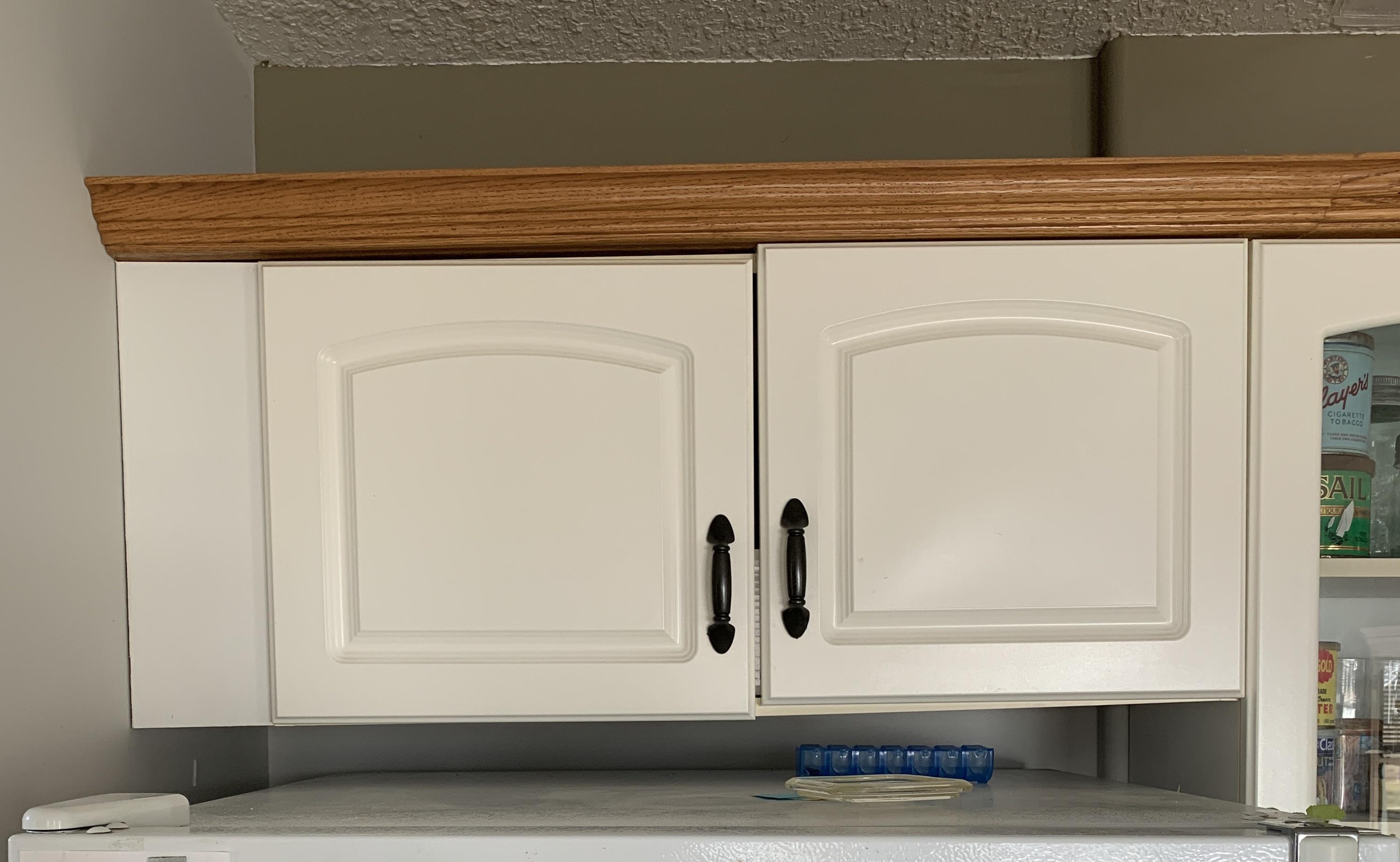 Upper kitchen cabinets with uneven alignment showing sagging cabinet doors before repair.