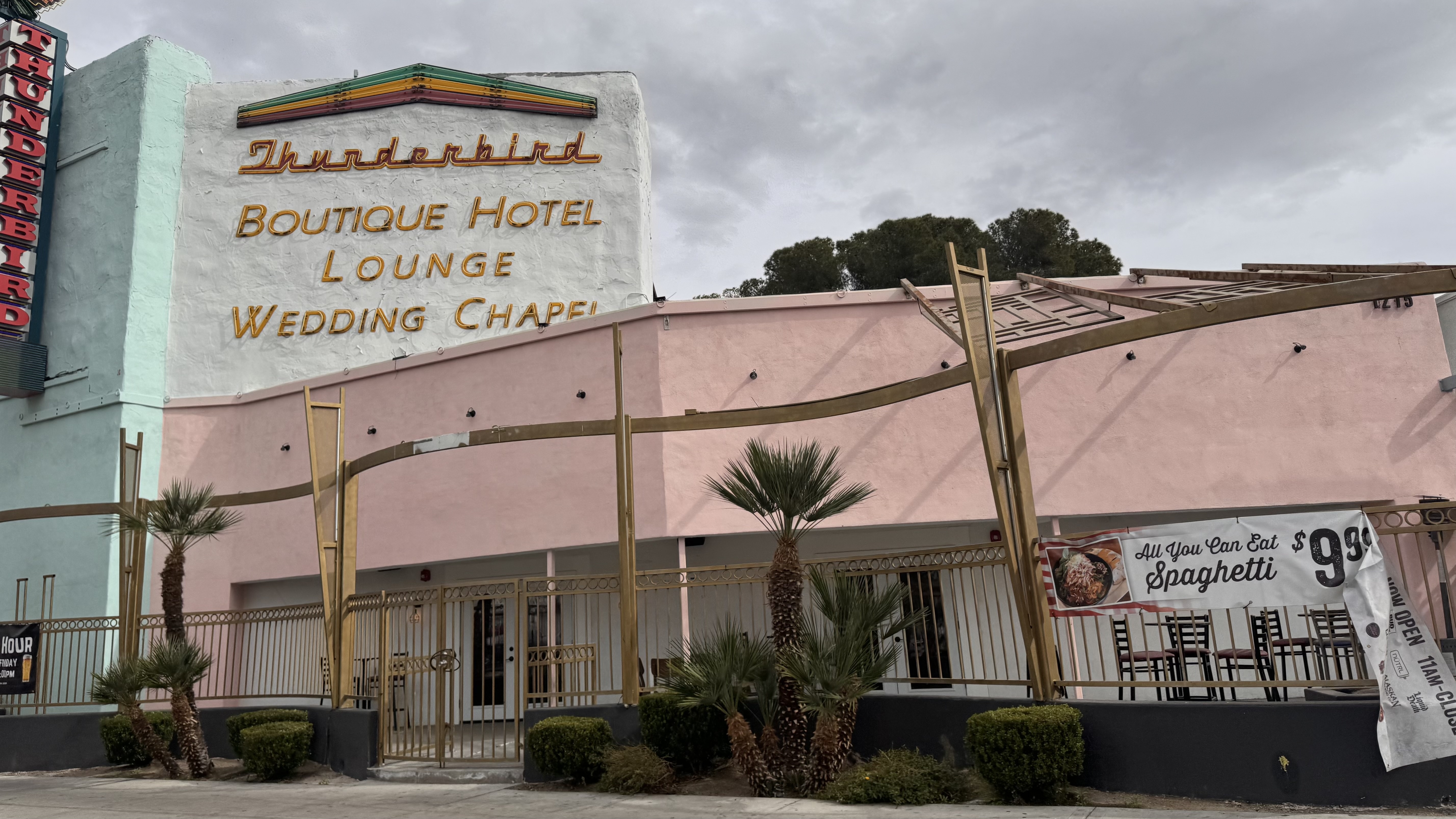Exterior of the Thunderbird Boutique Hotel and Wedding Chapel in Las Vegas, Nevada, featuring pink and white facade with gold lettering and palm trees.