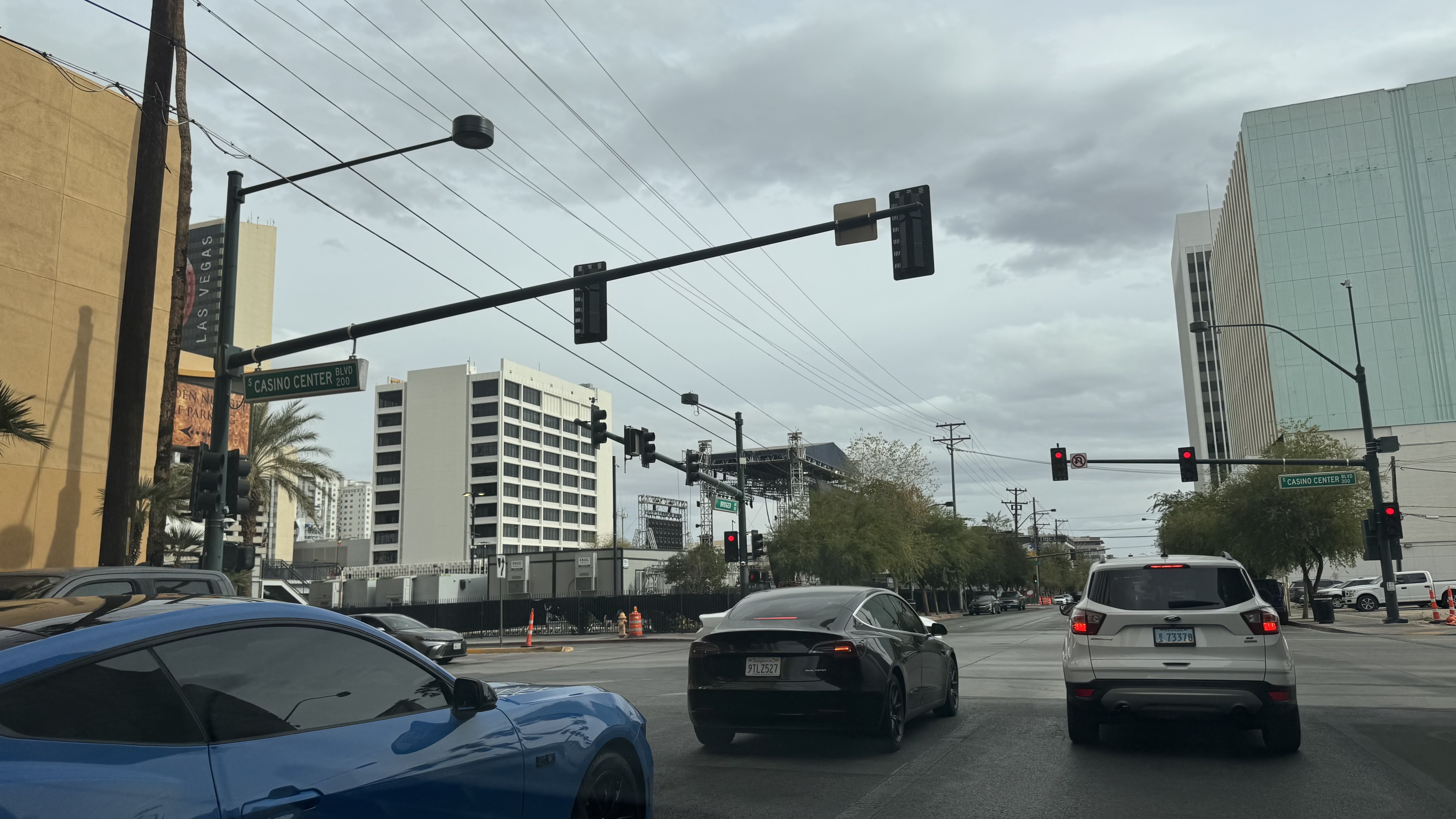 Urban intersection at Casino Center Blvd in Las Vegas with traffic lights, vehicles including a Tesla and Ford SUV, and tall buildings under overcast sky.