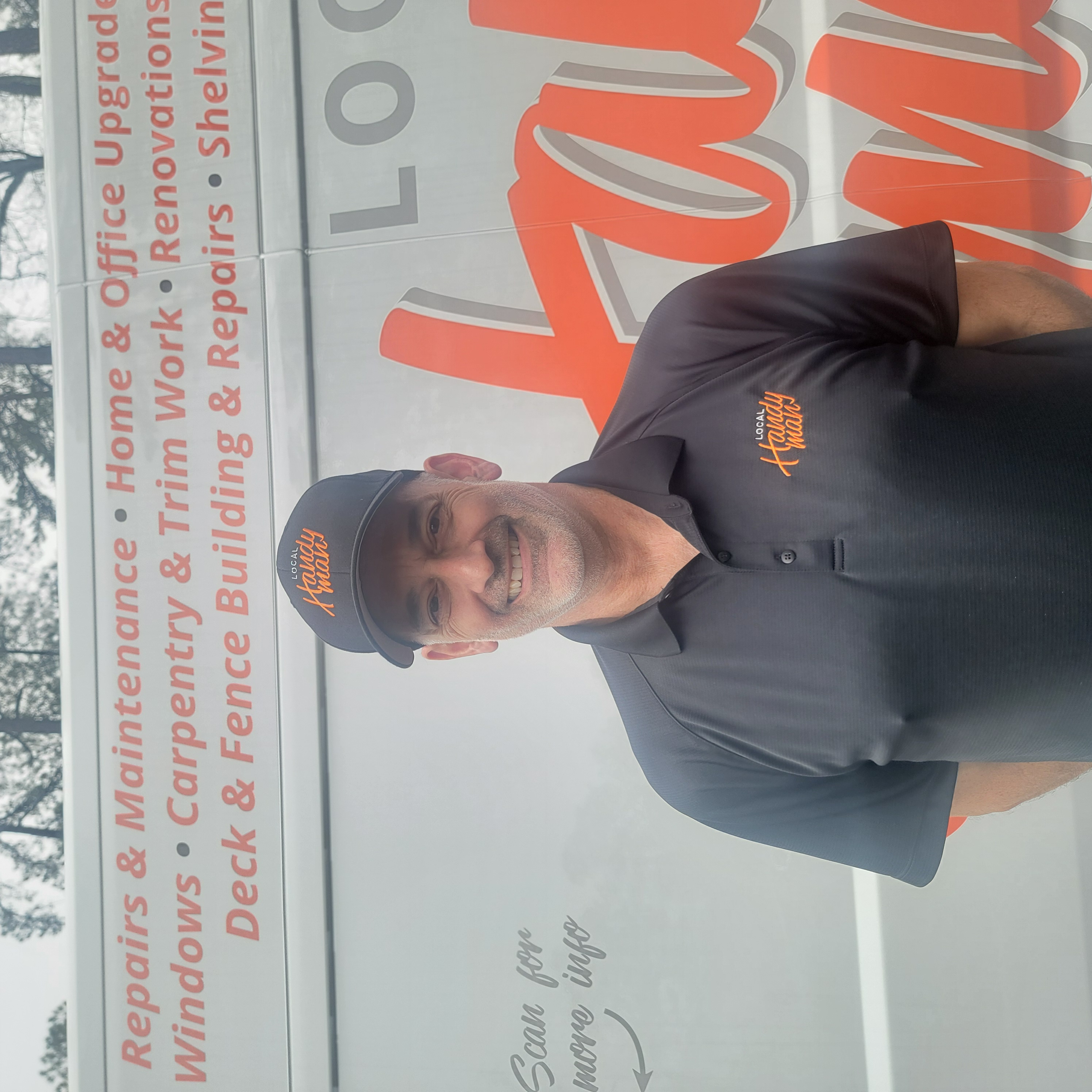 Keith Bowler wearing a Local Handyman cap and polo, standing in front of a company van.