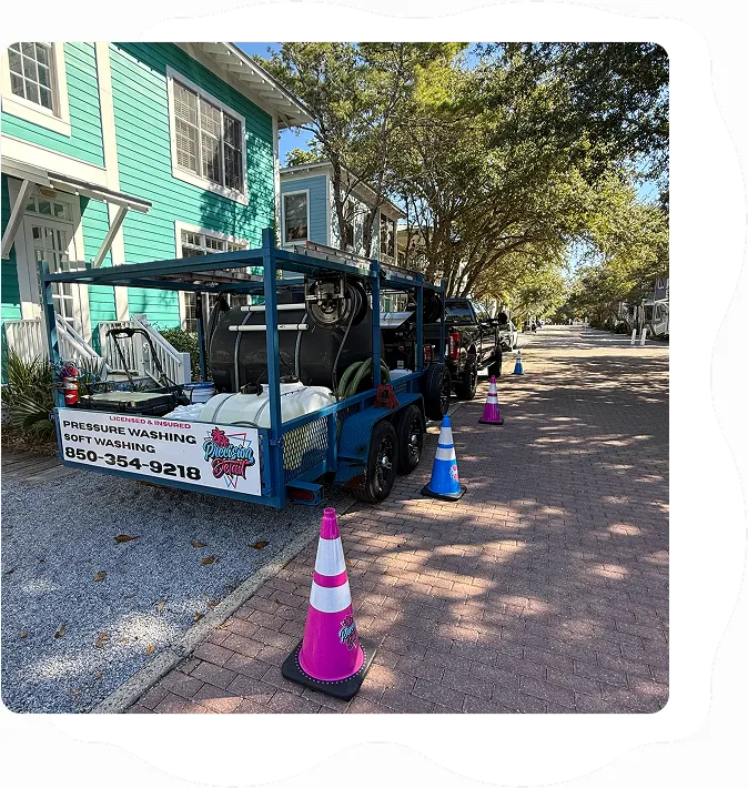 precision detail pressure washing trailer parked outside a home, with pink and blue safety cones and soft washing equipment visible.