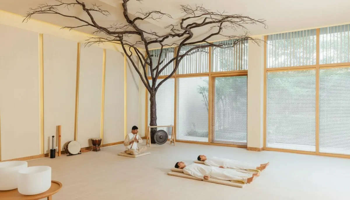 Pale light pouring into a cabin through a small window illuminates two unmade beds