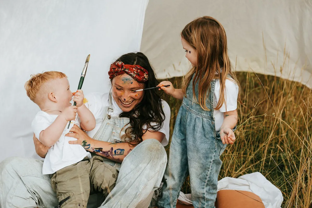 Suffolk Photographer taking photos family laughing and playing with paint in a field during a family photoshoot in bury st Edmunds