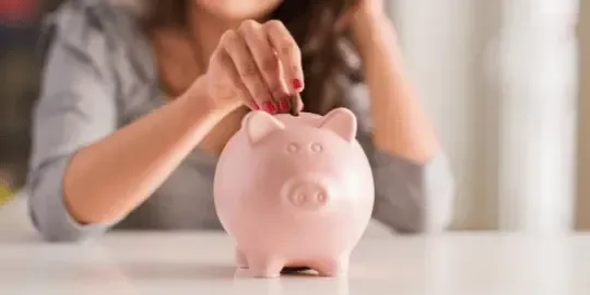 Person putting coins into a piggy bank to reduce IRS payments and save on back taxes
